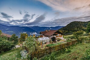 Ein Haus mit Anbauten, umgeben von einem Holzzaun und üppiger Vegetation.