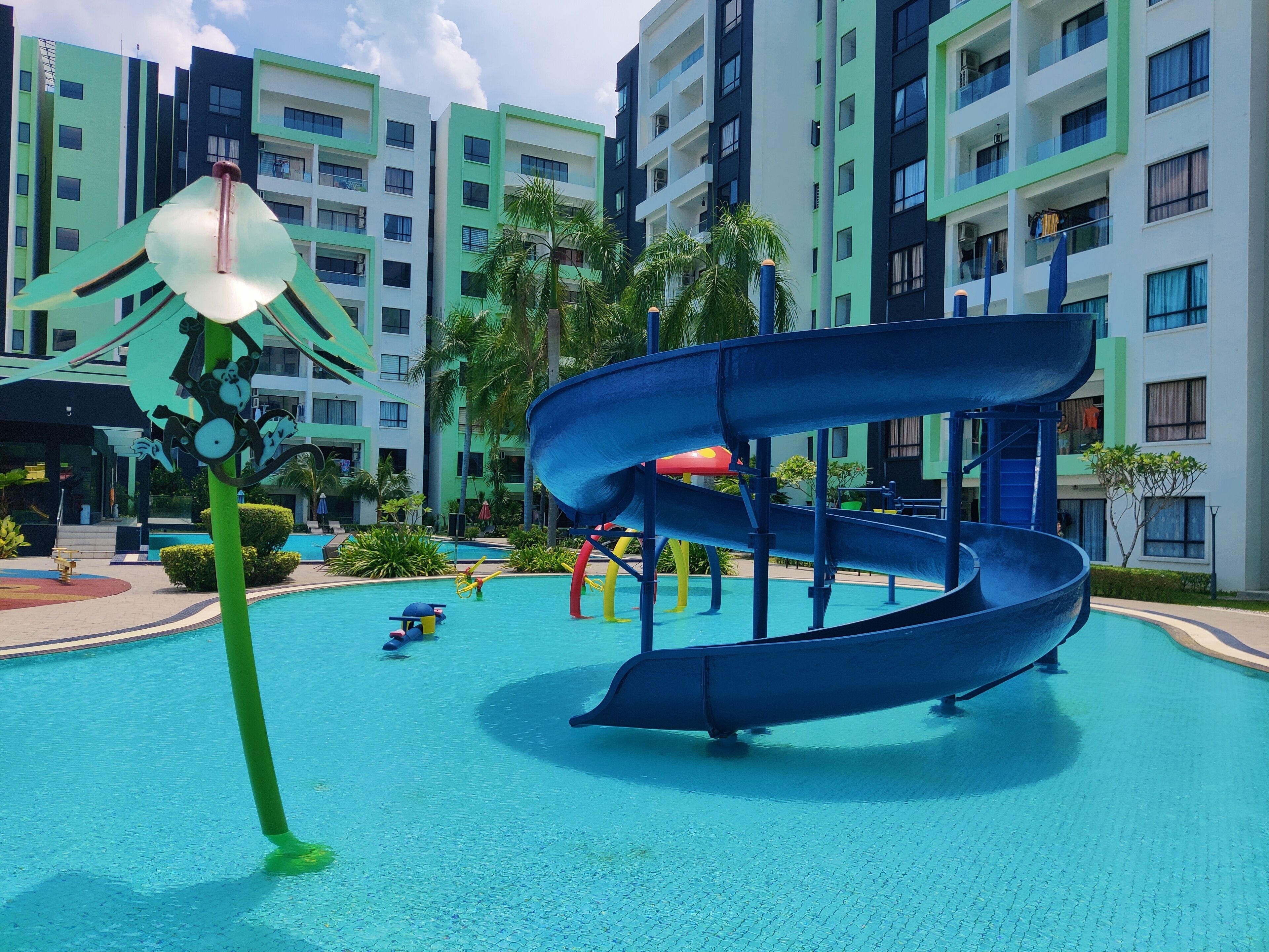 A water park with a blue slide and a green decorative structure.