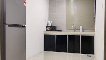 A compact kitchen with a refrigerator, microwave, and a small countertop with a kettle.