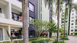 Un bâtiment moderne doté de balcons, d’un espace extérieur aménagé et d’une végétation luxuriante.