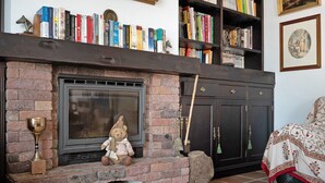 Una chimenea con una figurita de oso, estanterías llenas de libros y una cama con colcha estampada.