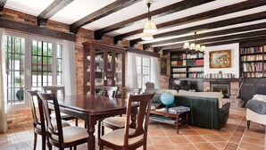 Un comedor con una mesa y sillas de madera, chimenea y una estantería.