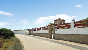 Una carretera pavimentada con un muro de piedra y un edificio con tejado de tejas.