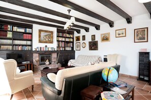A living room with a fireplace, bookshelves, a sofa, a globe, and a television.