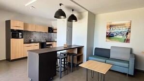A modern kitchen with a central island, bar stools, a sofa, and a coffee table. - Accessible apartment for 4, beach, heated pool, parking, pets allowed (La Tranche-sur-Mer)