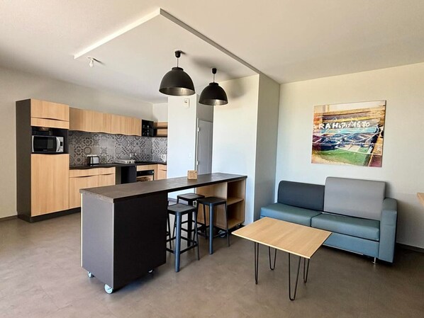A modern kitchen with a central island, bar stools, a sofa, and a coffee table.