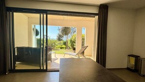 A room with a large sliding glass door leading to an outdoor patio area with a table, chairs, and a sun lounger. - Accessible apartment for 4, beach, heated pool, parking, pets allowed (La Tranche-sur-Mer)