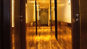 A hallway with polished wooden floors and dark wooden doors. - Hotel Dalon (Mumbai)