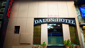 The exterior of Dalon Hotel with a signboard, entrance, and potted plants. - Hotel Dalon (Mumbai)