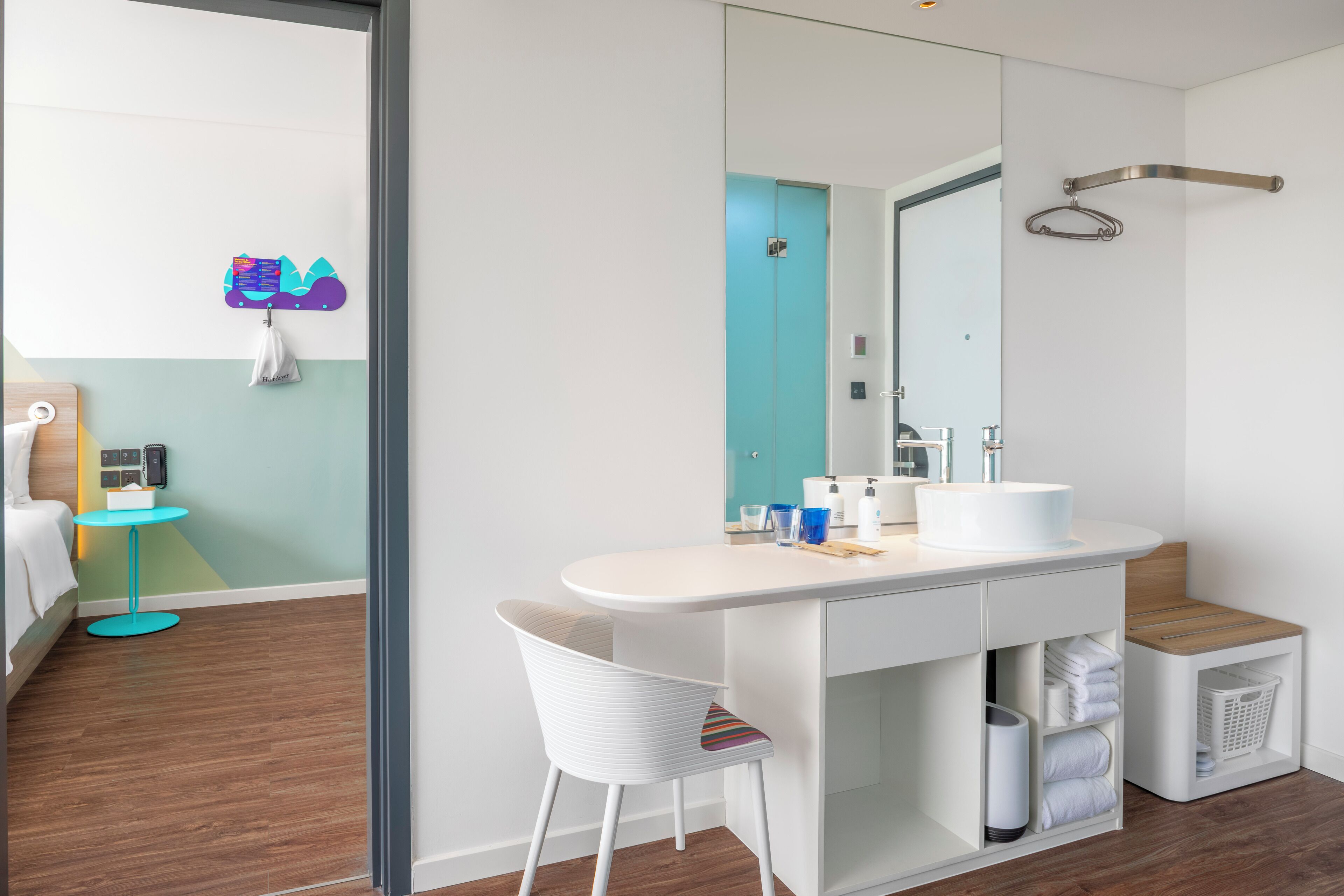 Une salle de bain moderne avec un meuble-lavabo blanc, un grand miroir et un espace douche.
