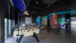 A modern indoor space with a foosball table, seating area, and a large wall mural.