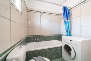 Un bagno con una vasca, un water e una lavatrice.