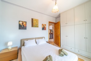 A bedroom with a bed, nightstand, wardrobe, and artwork on the wall.