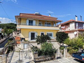 Un edificio a due piani con un balcone, un'antenna parabolica e un cancello.