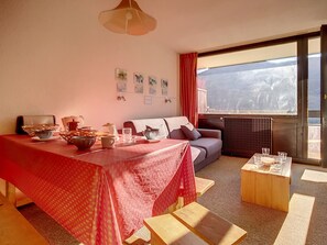 Quarto aconchegante com uma mesa de jantar posta para o café da manhã, um sofá e uma grande janela com vista.