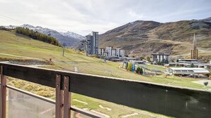 A view of a town with modern buildings, a river, and mountains in the background. - Bright apartment for 6, ski-in/ski-out, south balcony (Les Menuires)