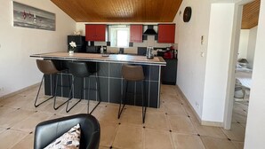 Uma cozinha compacta com uma ilha central, banquetas e teto de madeira.