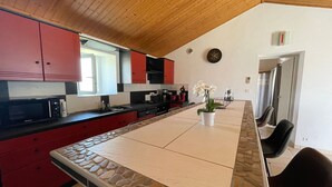 Cozinha com armários vermelhos, micro-ondas e área de jantar com mesa e cadeiras.