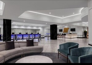 A modern lobby with a reception desk, seating area, and a marble column. - Villa on the Strip (Las Vegas)
