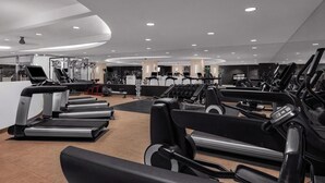Une salle de sport moderne dotée de nombreux tapis de course, d’appareils d’exercice et d’un intérieur propre et bien éclairé.