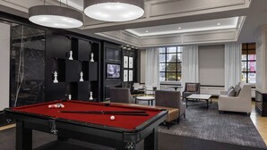 Un salon moderne avec une table de billard, un canapé et un téléviseur.