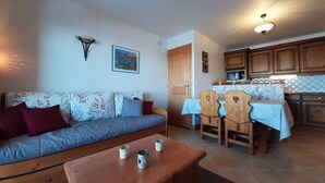 Ein gemütliches Wohnzimmer mit einer Couch, einem Holztisch und einem Essbereich mit Tisch und Stühlen.