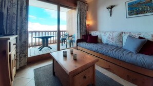 Ein gemütliches Wohnzimmer mit einer Holzsofa, einem kleinen Holztisch und einem Balkon mit Bergblick.