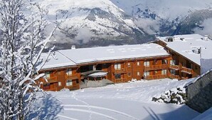 Eine Holzhütte mit schneebedecktem Dach, umgeben von Bergen und Schnee.