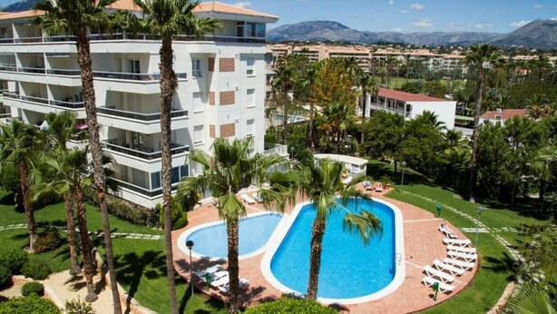 Ein Hotel mit Pool, Palmen und einem Bergpanorama.
