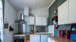 Une cuisine compacte équipée d’une cuisinière, d’un four, d’un lave-vaisselle et d’une hotte aspirante intégrée.