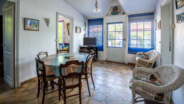 Un coin repas avec une table et des chaises, un téléviseur et des meubles en osier.