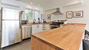 A modern kitchen with a stainless steel refrigerator, wooden countertop, and a large island. - 4 Storey Ski In/Out Mountain Home in Tremblant (Mont-Tremblant)