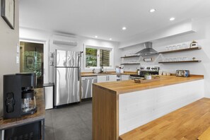 Een moderne keuken met een centraal eiland, roestvrijstalen apparatuur en een raam met uitzicht op groen.