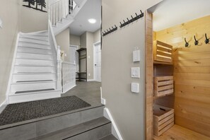 A staircase with a white railing and a wooden wall with a coat rack. - 4 Storey Ski In/Out Mountain Home in Tremblant (Mont-Tremblant)