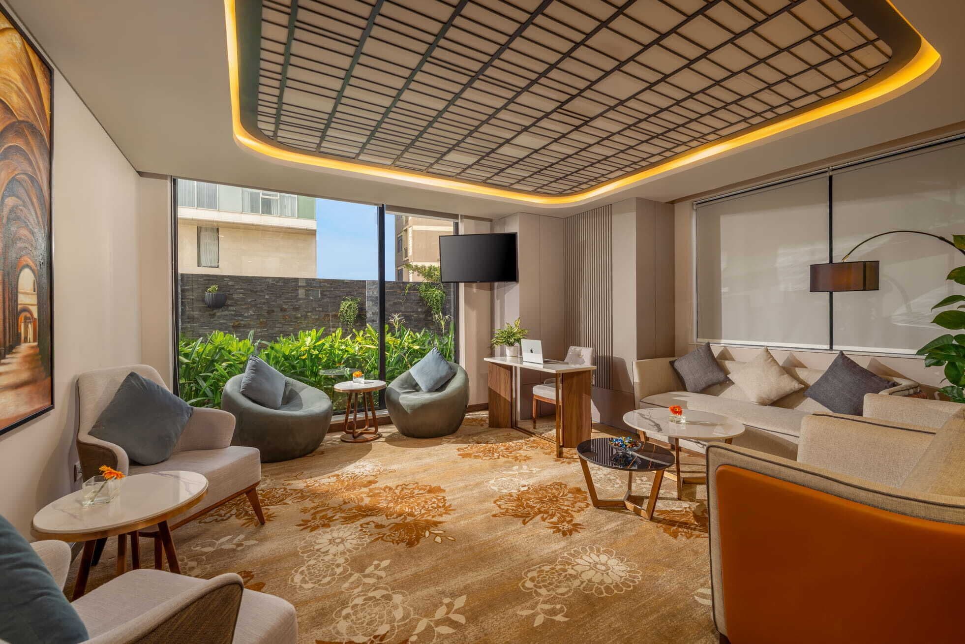 A modern living room with a sofa, armchairs, a coffee table, and a TV.