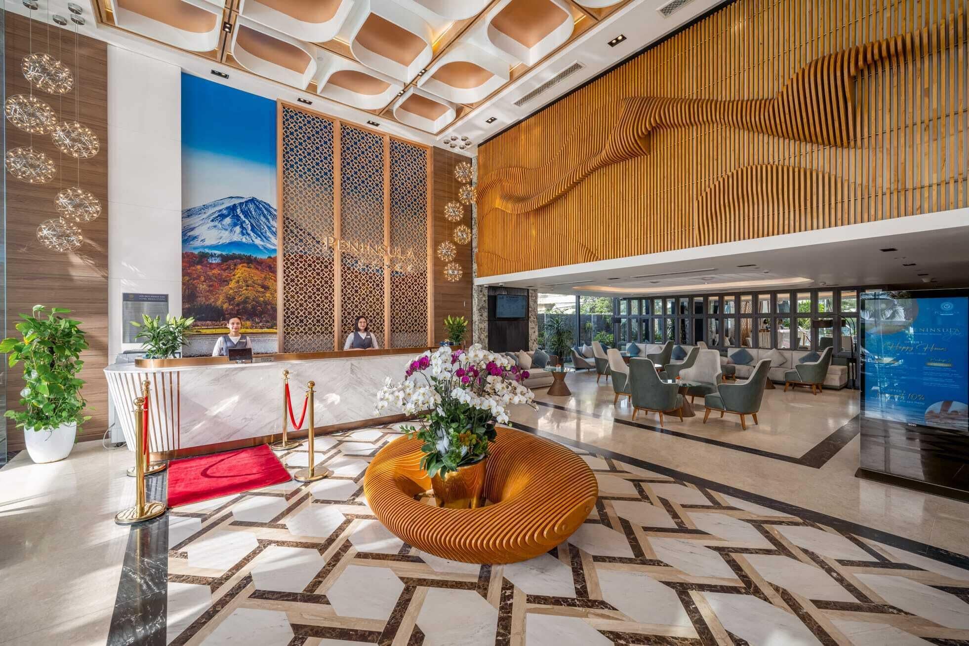 A hotel lobby with a reception desk, seating area, and a large wall mural.