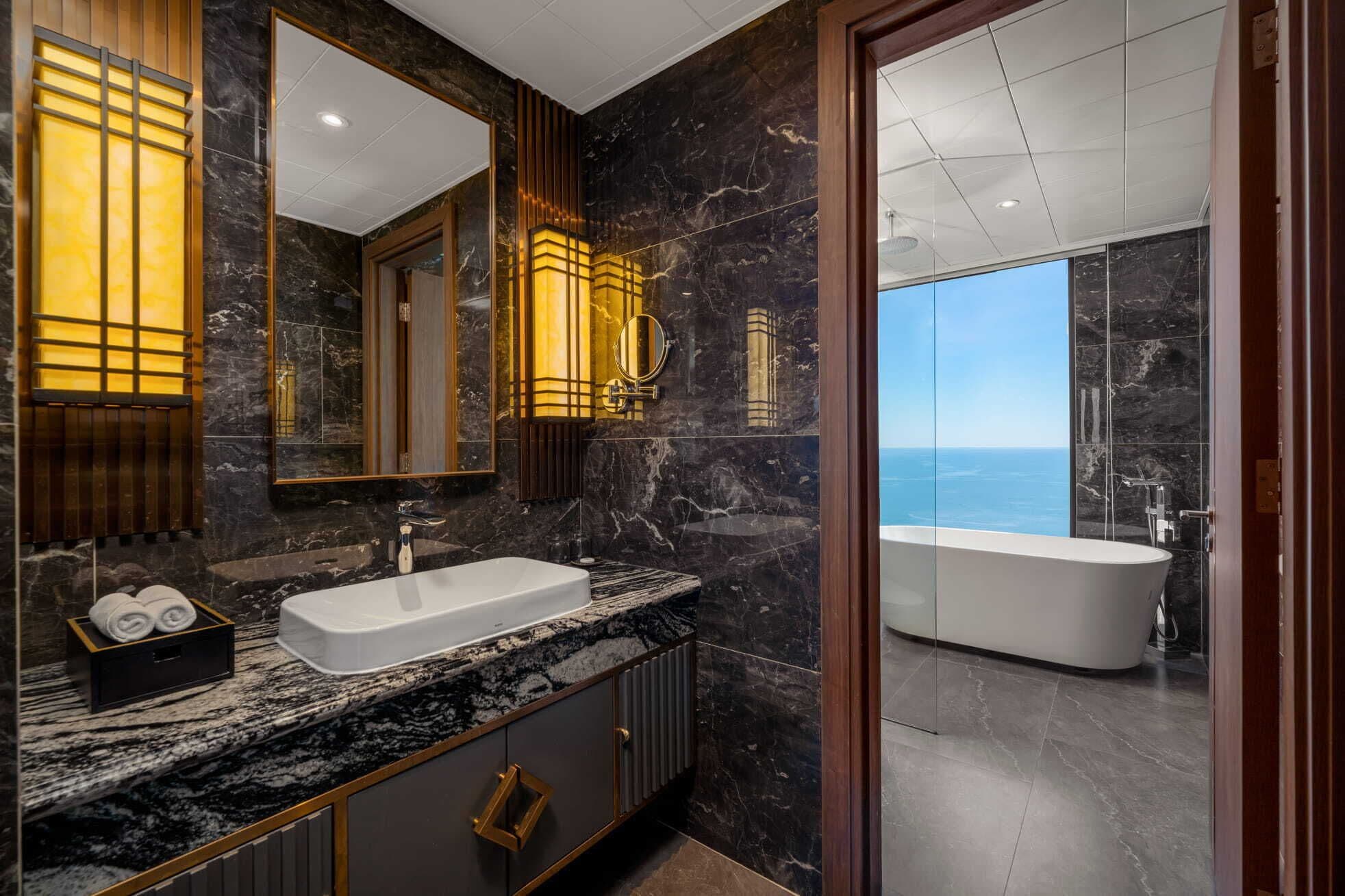 A modern bathroom with a large bathtub, a vanity with a marble countertop, and a large mirror.