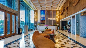 A modern lobby with a reception desk, seating area, and a large window offering a view of the outdoors.