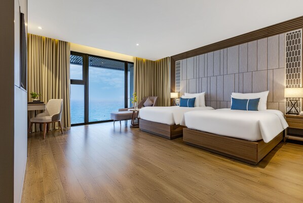Habitación de hotel moderna con dos camas, un escritorio, una silla y un gran ventanal con vistas al mar.