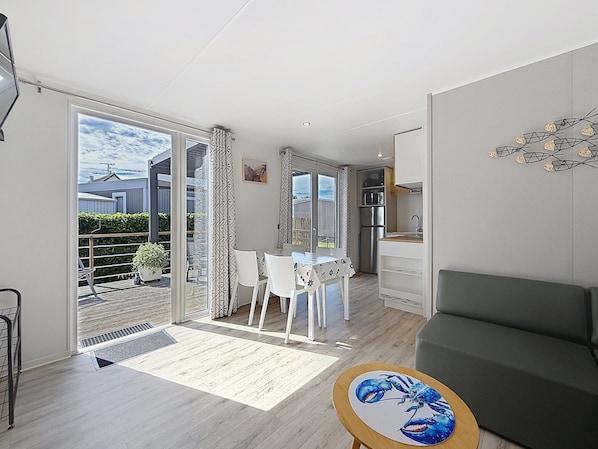 A modern apartment with a dining area, kitchenette, and a balcony with a view.