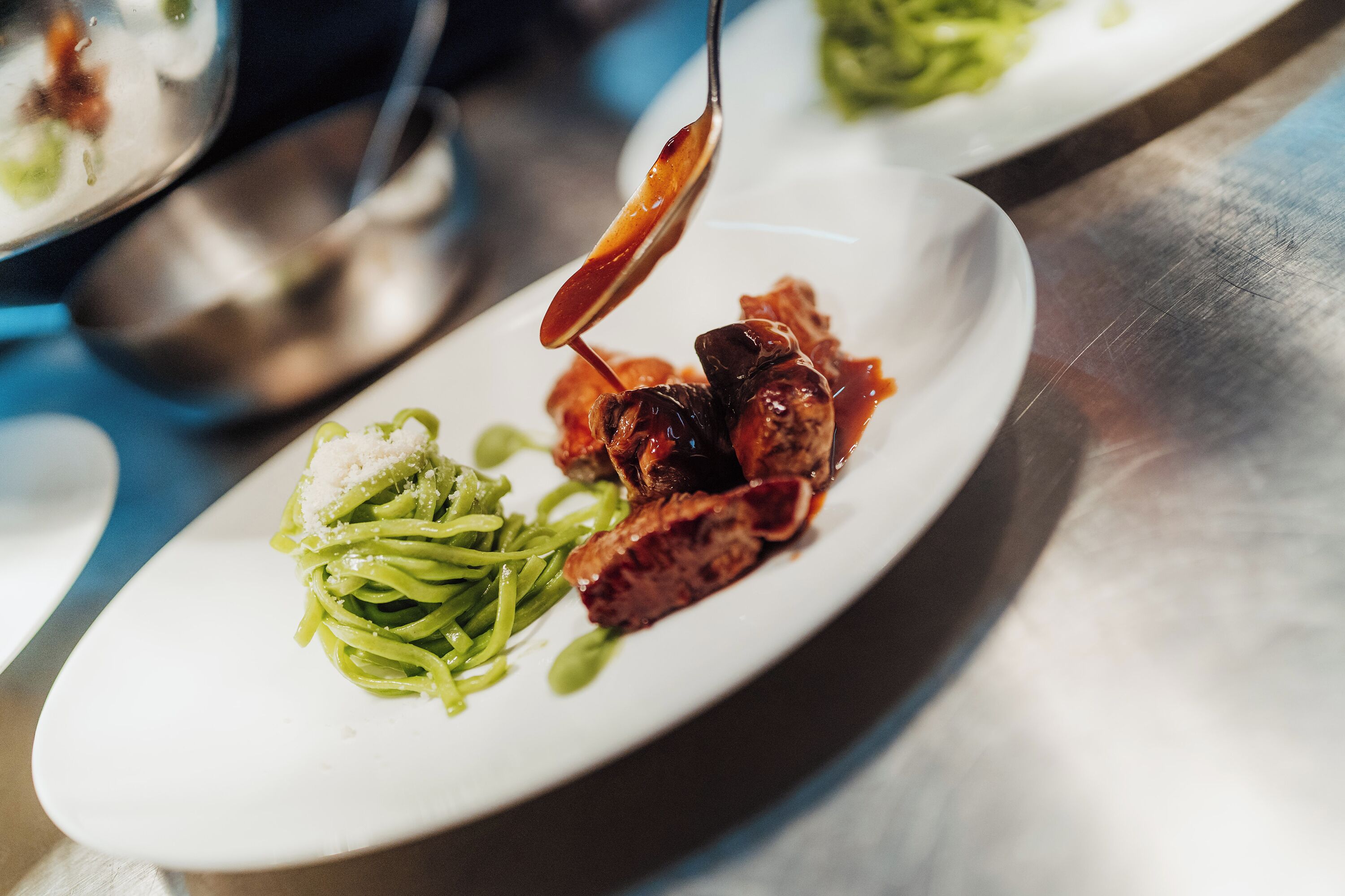 Une vue rapprochée d’une assiette contenant des pâtes, de la viande et une sauce.