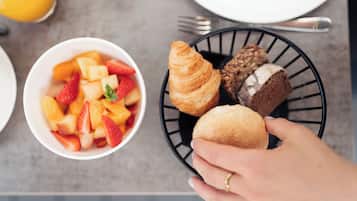 A breakfast setting with a bowl of fruit and pastries on a tray.