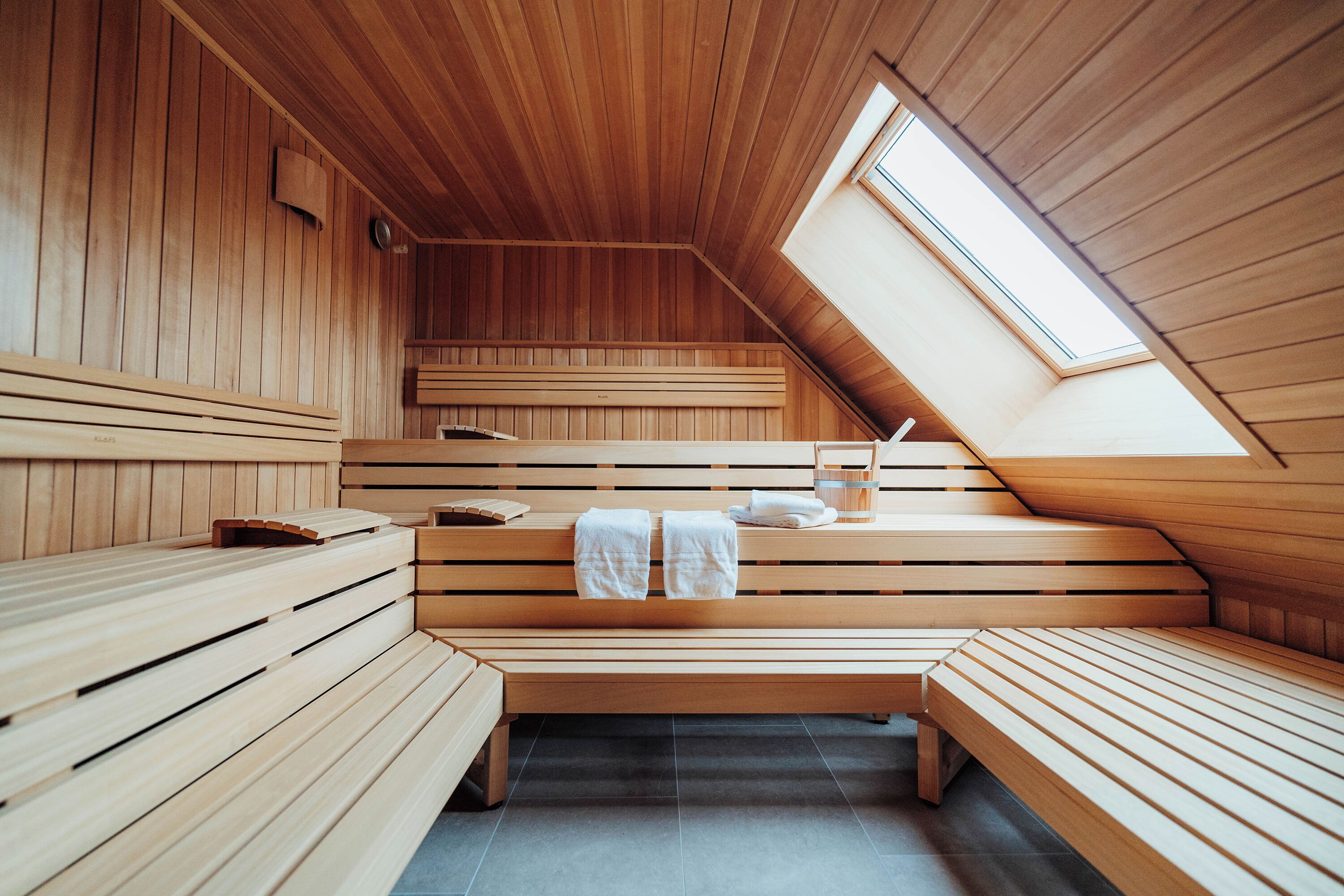 A sauna with wooden benches and a skylight.