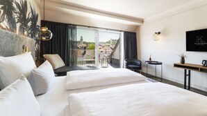 Habitación de hotel con una cama grande, un escritorio, una silla y vista a la ciudad.