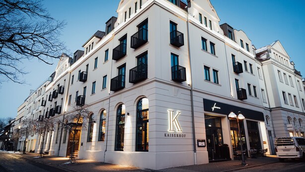 Un hotel de varios pisos con un llamativo logo 'K', grandes ventanales y un estilo arquitectónico clásico.
