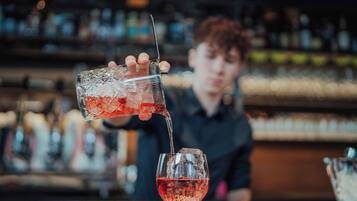 A bartender pouring a drink into a glass.