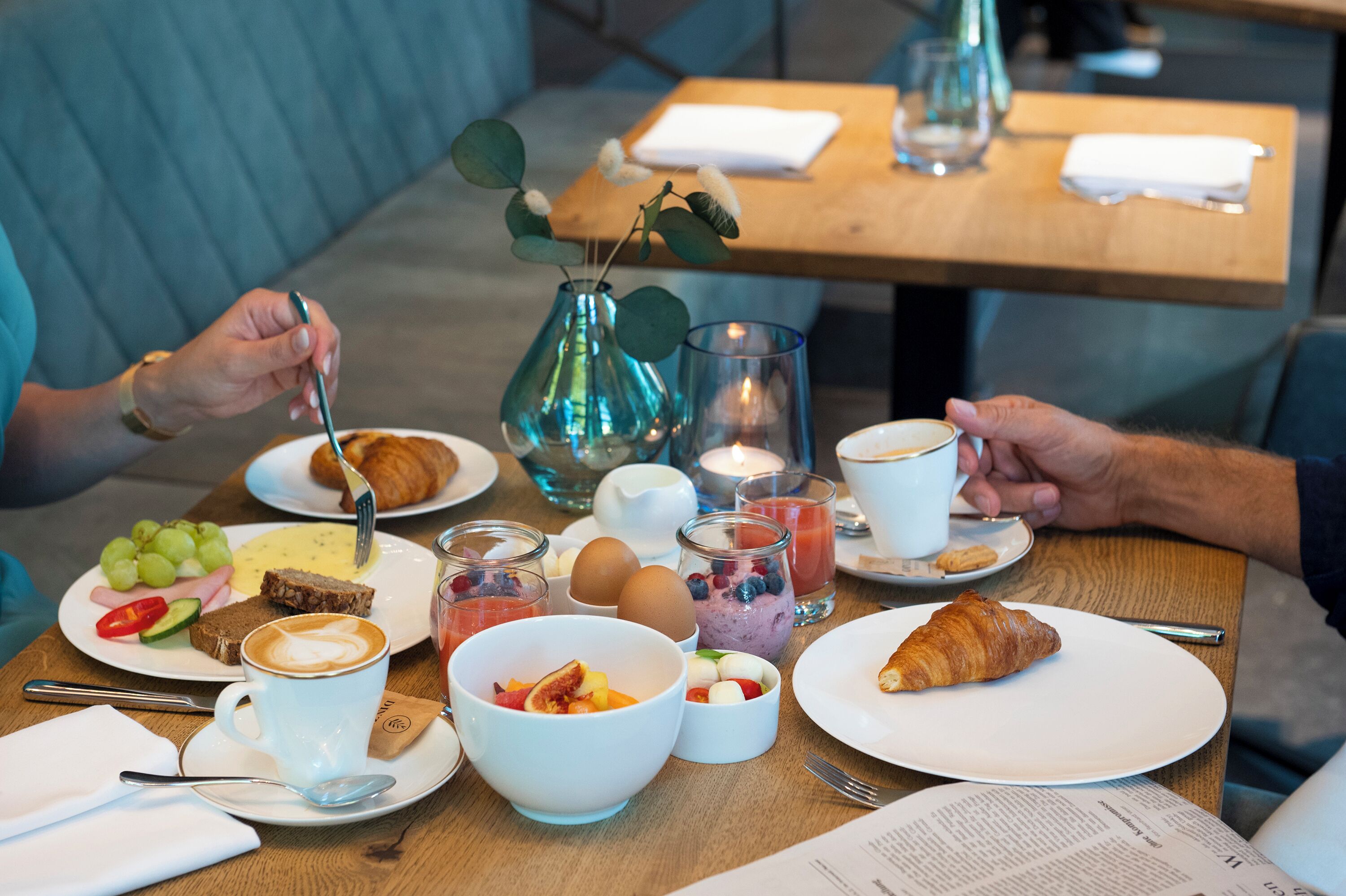 A breakfast setting with plates of food, cups of coffee, and a croissant.