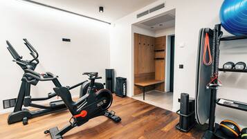 A modern home gym with stationary bikes, a rowing machine, and a weight bench.