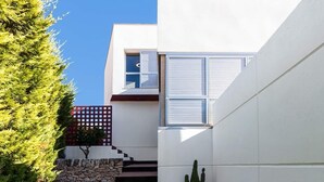 Una casa moderna con fachada blanca, una escalera de piedra y un cactus en el jardín.