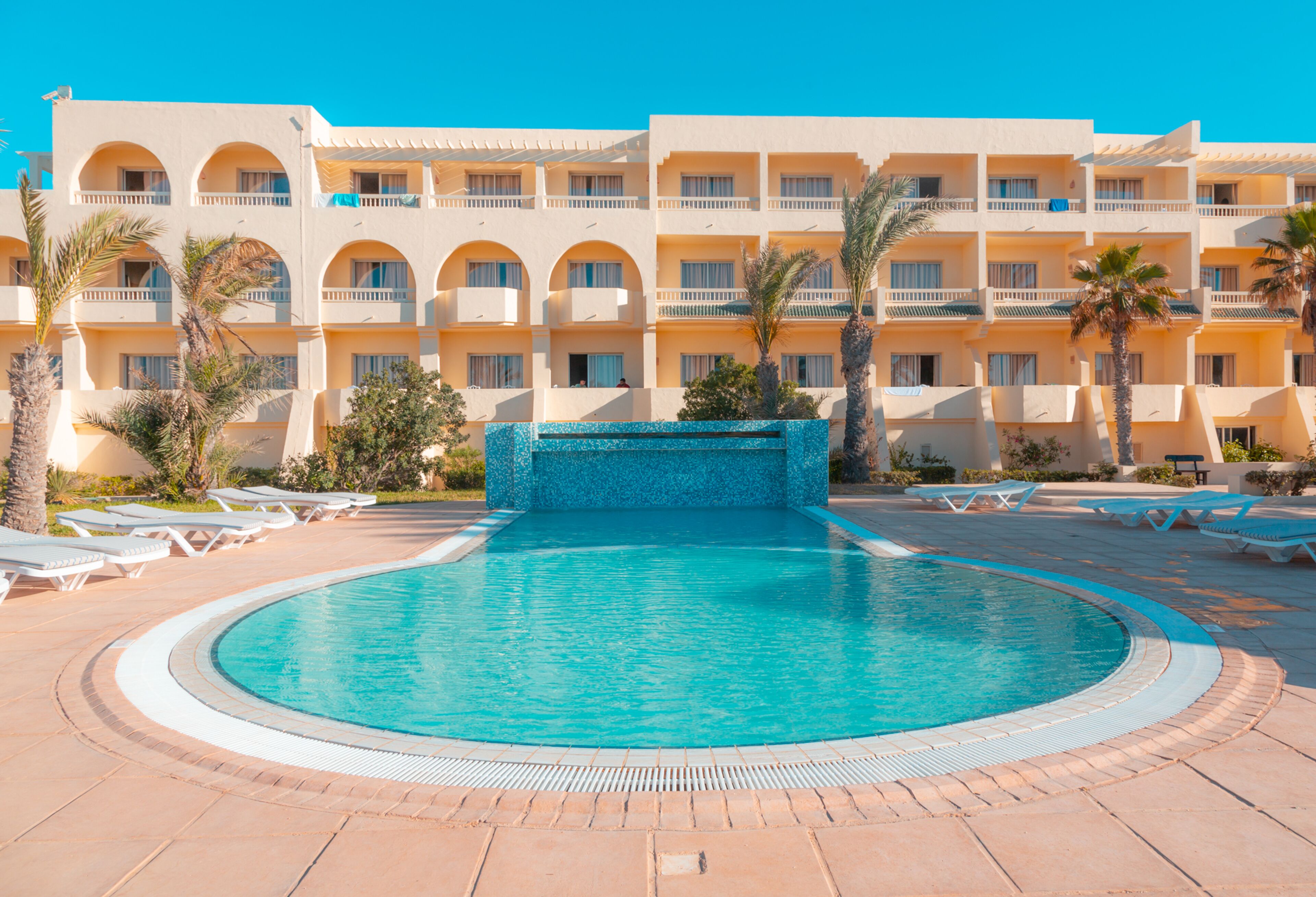 Una piscina techada, una piscina al aire libre, sombrillas